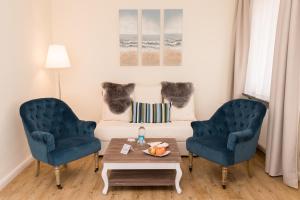 a living room with two blue chairs and a couch at Das Frühstückshotel Büsum in Büsum