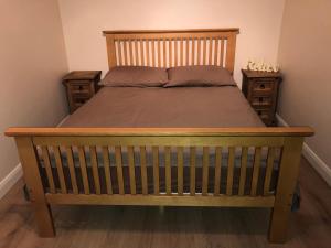a bed with a wooden frame and two night stands at California Chalet & Touring Park in Wokingham