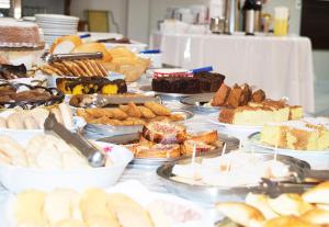 una mesa llena de diferentes tipos de pasteles y repostería en Hotel Fiorini Ltda en Pinhalzinho