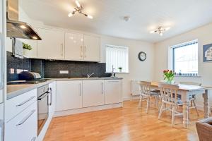 a kitchen with white cabinets and a table with chairs at SeaQuest 5 in Newquay