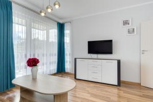 a living room with a table and a tv at Elite Apartments Family City Center in Gdańsk