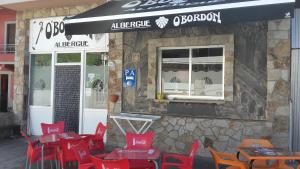 a group of red chairs and tables outside of a restaurant at Albergue O Bordón in Cee