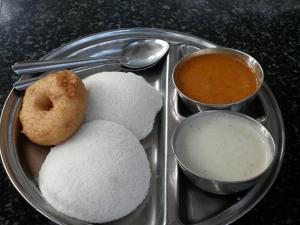 a tray with rice and a donut and two dips at Minerva Residency in Bangalore