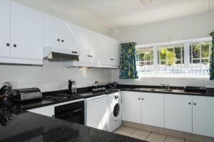 a kitchen with white cabinets and a dishwasher at Long Island 42 in Ballito +6 photos
