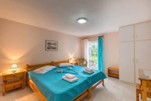 a bedroom with a bed with blue sheets and a window at Ormos Drepanou Apartments in Lygia