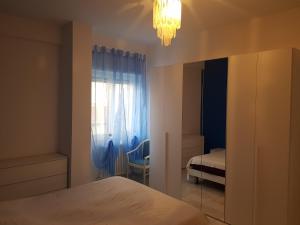 een slaapkamer met een bed, een raam en een kroonluchter bij La casa di Cri con servizio spiaggia incluso! in San Benedetto del Tronto