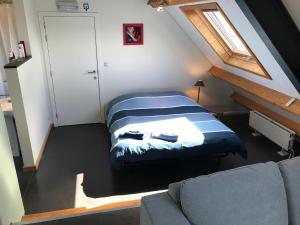 Habitación en el ático con cama y sofá en Rap 'n Holiday Home, en Sint-Denijs-Westrem