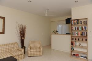 a living room with two chairs and a book shelf at Yolanda Studios in Paralia Agias Foteinis