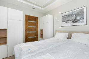 a white bedroom with a large bed with white sheets at Holiday House Nemo by Renters in Międzywodzie