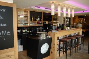 a bar in a restaurant with stools and wine bottles at Hotel Dein Franz - Bistro, Kaffeebar & Outdoor-Lounge - in Bad Füssing