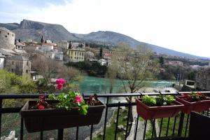 three potted plants on a balcony overlooking a river at Pansion Villa Nur in Mostar
