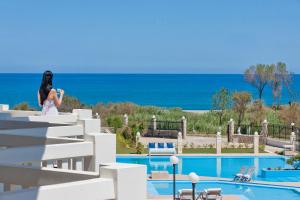 a woman standing on steps near a swimming pool at Mrs Chryssana Beach Hotel Adults Only in Kolymvari