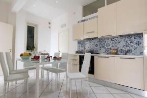 サレルノにあるMare mìaの白いキャビネット、テーブルと椅子付きのキッチンが備わります。