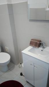 a white bathroom with a sink and a toilet at Vasco Santana Guesthouse in Odivelas