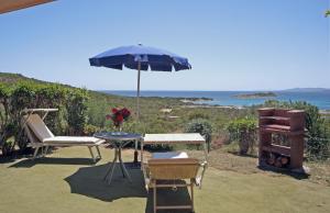 a patio area with chairs, tables and umbrellas at Residence Baia Salinedda in San Teodoro