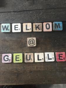 een groep letters en cijfers op een houten muur bij @ geulle in Guelle