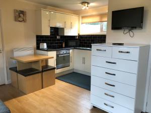 a kitchen with white cabinets and a flat screen tv at California Chalet & Touring Park in Wokingham