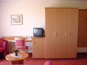 レンツキルヒにあるHotel Gasthof Straubのテーブル、テレビ、キャビネットが備わる客室です。