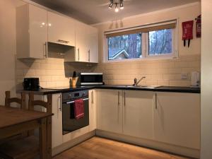 a kitchen with white cabinets and a sink and a stove at California Chalet & Touring Park in Wokingham +10 photos