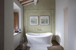 a white tub in a bathroom with green walls at Borgo Argiano in Castelnuovo Berardenga