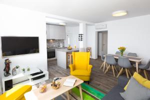 een woonkamer met een gele stoel en een keuken bij Villa Pergola-Apartment Toni in Mlini
