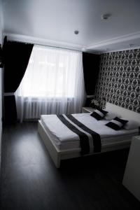 a bedroom with a large bed with a window at Hotel Khozyayushka in Perm