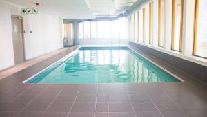 a swimming pool in a building with a tile floor and windows at Penthouse Suite at Cartwrights Corner in Cape Town
