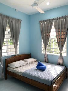 a bed in a room with blue walls and windows at Twin Homestay B in Kuala Terengganu