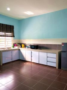 a kitchen with white cabinets and a blue wall at Twin Homestay B in Kuala Terengganu
