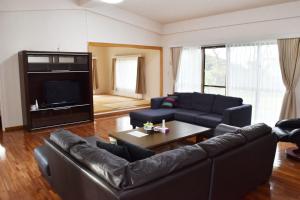 a living room with a couch and a tv at Cottage Sachi in Nakijin