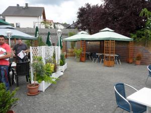 a patio with tables and umbrellas and potted plants at Landhaus Schaaf in Runkel