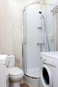 ein Badezimmer mit einer Dusche, einem WC und einer Waschmaschine in der Unterkunft WSTApartments Młynarska 13 in Warschau