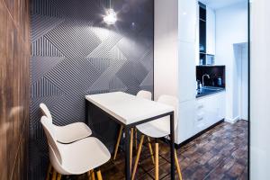 a small kitchen with a white table and white chairs at Arkadija - Filatova in Lviv