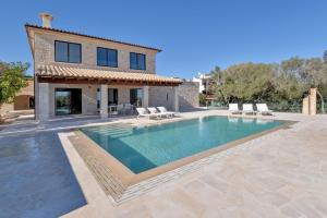 eine Villa mit einem Pool vor einem Haus in der Unterkunft Villa Corso in Portocolom