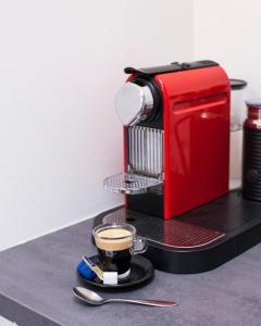 a red coffee machine sitting on a table with a cup of coffee at Kuwadro Guesthouse Centrum in Amsterdam