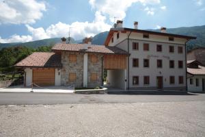 a large white building with mountains in the background at Albergo diffuso Valcellina e Val Vajont in Claut in Claut
