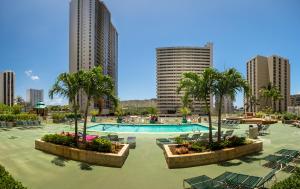 un complexe avec une piscine, des palmiers et des bâtiments dans l'établissement Hawaiian Sun Holidays, à Honolulu