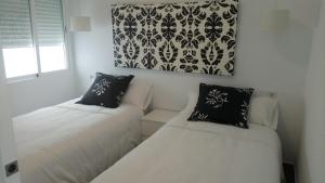 コルドバにあるLuxury Viana Apartmentsの白い壁の客室で、ベッド2台、窓が備わります。