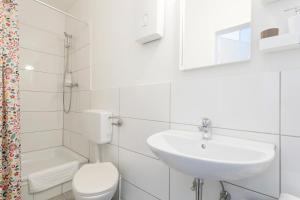 een witte badkamer met een wastafel en een toilet bij Family Studio Apartment for 4 in Berlijn
