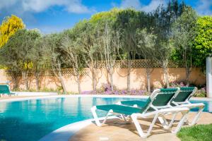 duas cadeiras de jardim sentadas ao lado de uma piscina em Casa da Montanha na Praia da Luz