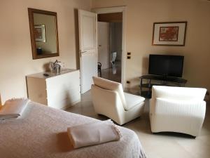 a bedroom with a bed and a chair and a television at Palazzo Sottile Meninni in Gravina in Puglia