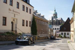ein altes Auto auf einer Straße neben einem Gebäude geparkt in der Unterkunft Hotel Alt Annaberg in Annaberg-Buchholz