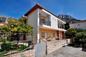 a white house with a balcony and a fence at Apartmani Ivana & Toni in Gradac