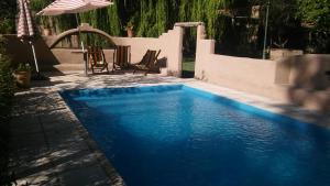 a blue swimming pool with chairs and an umbrella at Molino la Tebaida in San Martín