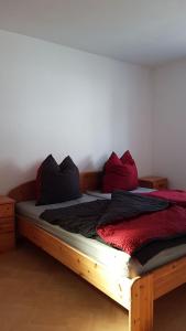 a bed with red and black pillows on it at Ferienwohnung am Hang in Ettenheim