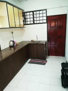 a kitchen with a red door and a white tile floor at Max Budget Hideout in Bayan Lepas