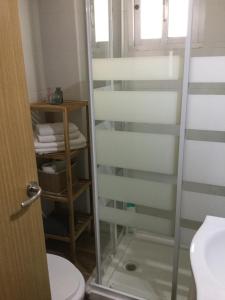 a bathroom with a glass shower door next to a toilet at Apartamentos MásBambú in Málaga