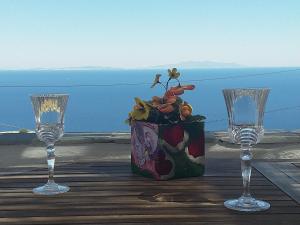 a table with two wine glasses and a vase with flowers at Amazing View Dream House in Chora Folegandros