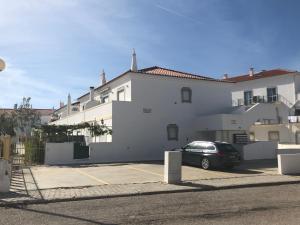 a white building with a car parked in a parking lot at Altura da Maré - Apartamento Duna in Altura