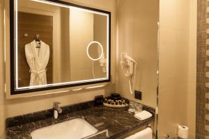 a bathroom with a sink and a mirror and a robe at Hm Commerce Hotel in Ankara